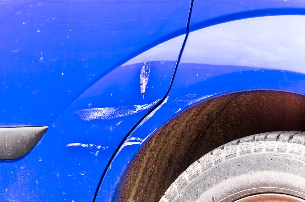 Blue scratched car with damaged paint in crash accident on the street or collision on parking lot in the city