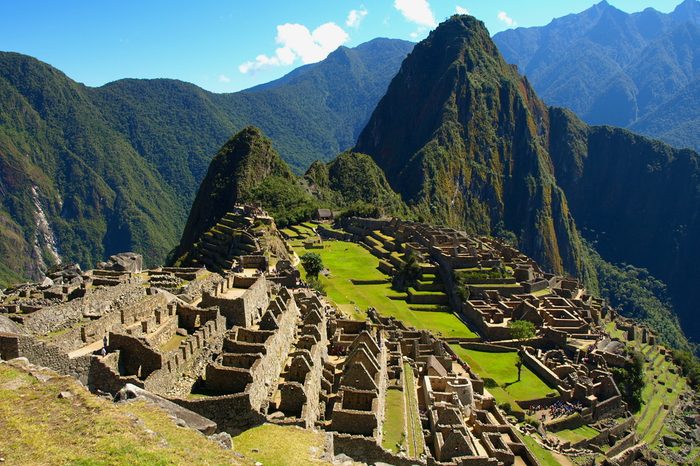 Machu Picchu in Peru - lost city of Incan Empire is UNESCO heritage. Sunny summer day with blue sky and clouds.