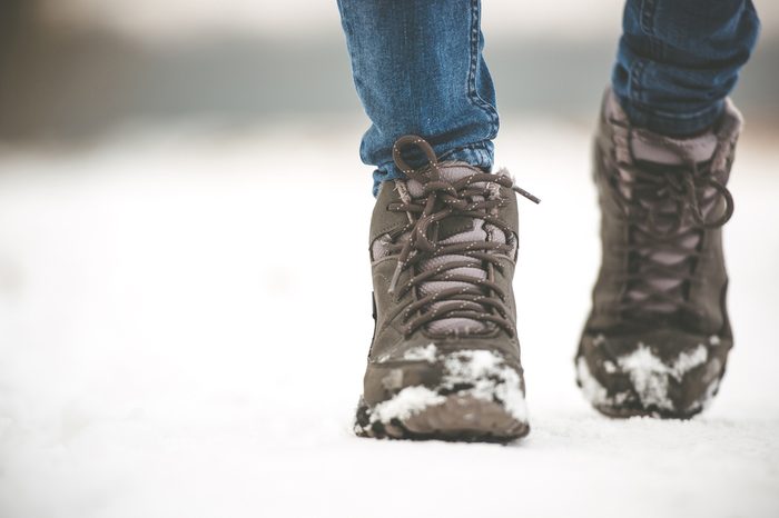 girl in winter boots walking on snowy road