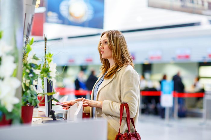 Tired woman at international airport in terminal at check-in desk. Upset sad business passenger waiting. Canceled flight due to pilot strike.