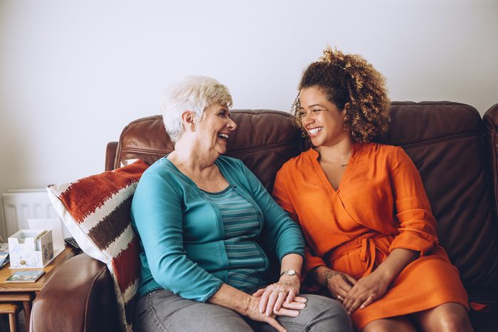 Senior woman enjoying a laugh with her granddaughter. They are sitting on the sofa together.