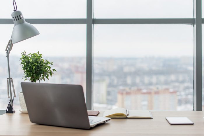 Workplace with notebook laptop Comfortable work table in office windows and city view.