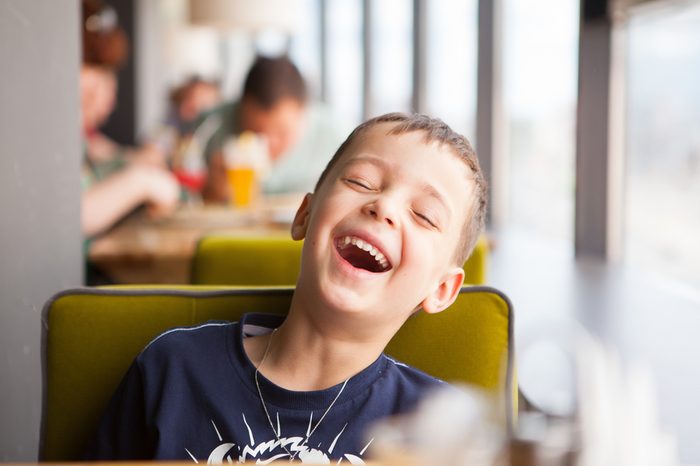 boy is laughing loudly in cafe