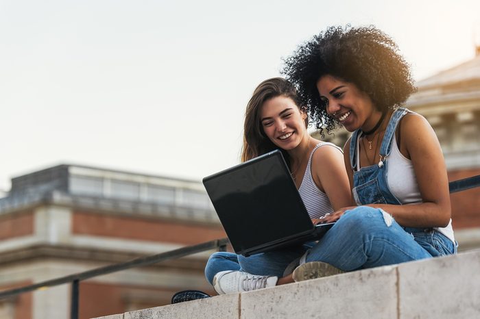 Beautiful women using a laptop in the Street. Youth concept.