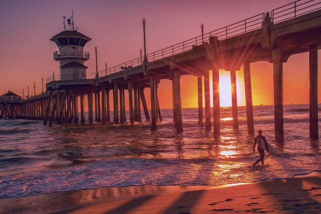 Silhouette of a surfer at sunset in front of the Huntington Beach Pier in California