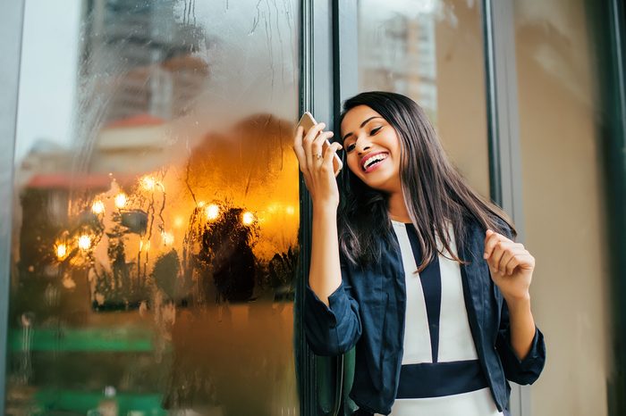 A happy young Indian woman looking in her phone and laughing