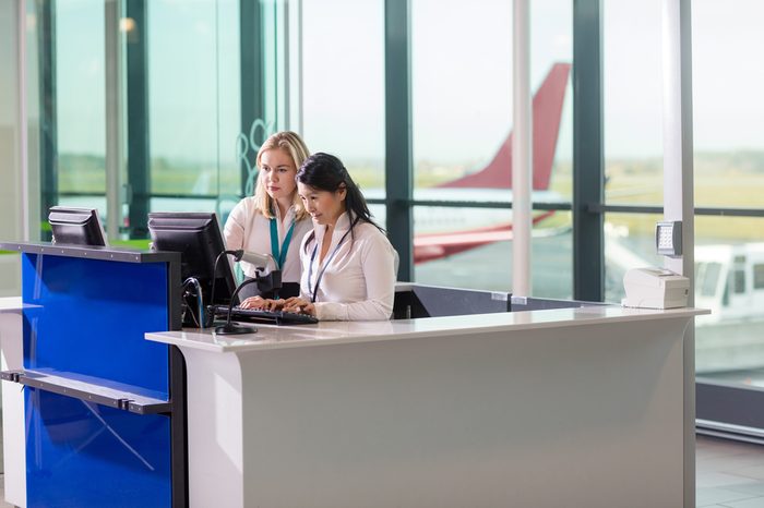 Ground Staff Using Computer At Counter In Airport