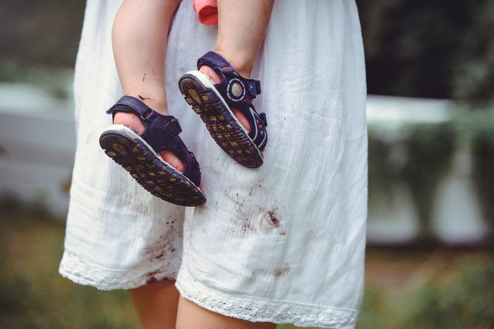 shod feet of a child in the arms of a mother, a white dress, stained with shoes, raising children and loving them