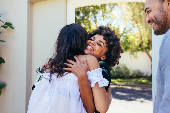 African woman greeting female friend for having a new house. Smiling young woman congratulating her friend. Couple welcoming friend for housewarming party.