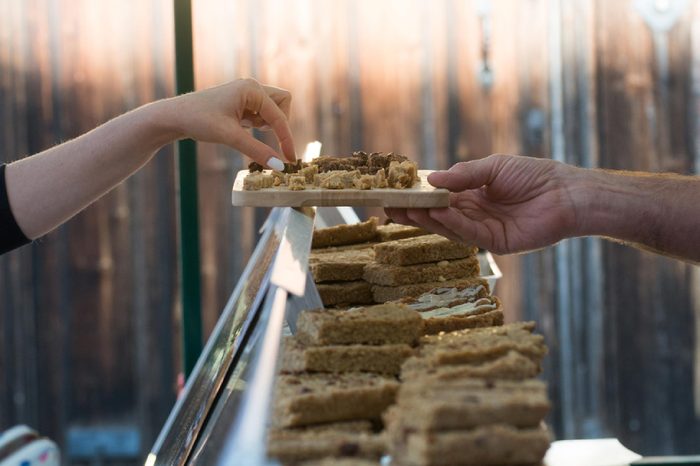 woman taking a sample of street food from a market stall