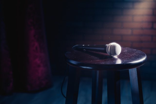 microphone on a wooden stool on a stand up comedy stage with reflectors ray, high contrast image