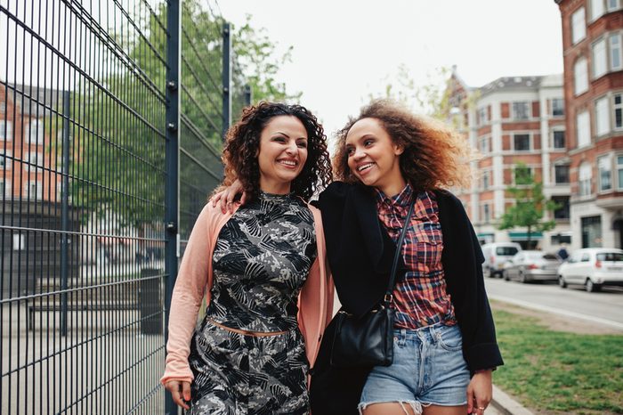 Two young women on the city street. Smiling young women walking along city street, outdoors.