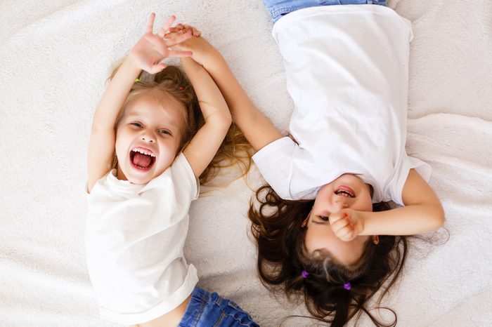 happy little girls lying on back top view sisters