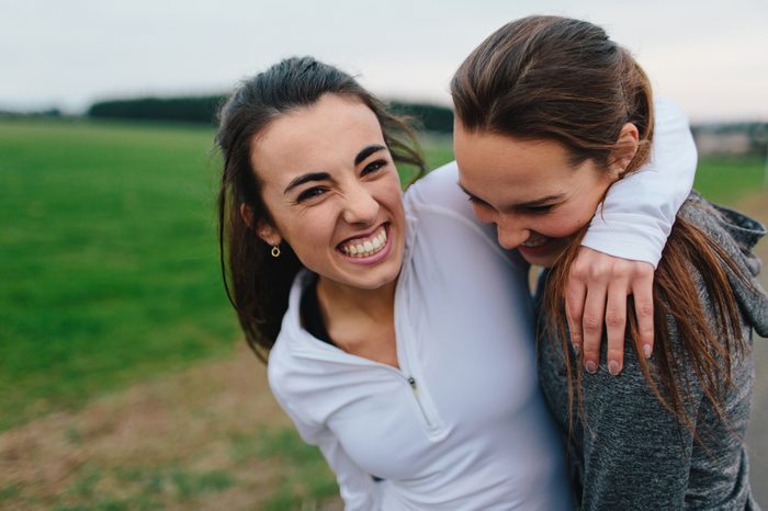 Young Adult Female Runners Arms Around each other smiling in country