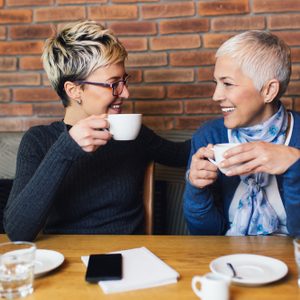 Senior mother sitting in cafe bar or restaurant with her middle age daughter and enjoying in conversation.