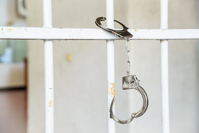 Closeup of unlocked handcuffs hanging on jail bars