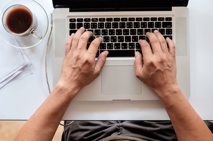 A man working on a white desk with a laptop.