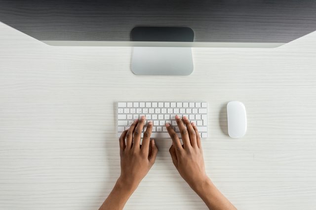 cropped shot of student typing on keyboard while working on computer