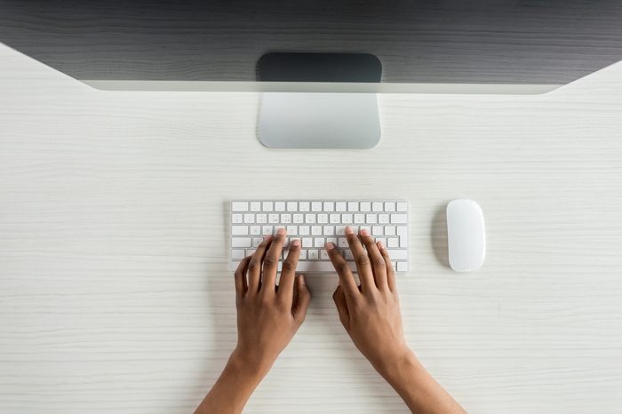 cropped shot of student typing on keyboard while working on computer