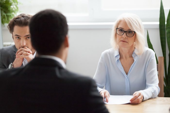 Serious attentive senior female hr manager employer listening to candidate at job interview, focused strict mature businesswoman thinking about hiring decision at difficult group negotiations concept