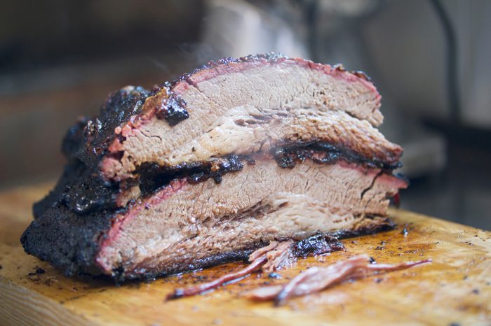 Two large pieces of smoked brisket meat on a wooden board