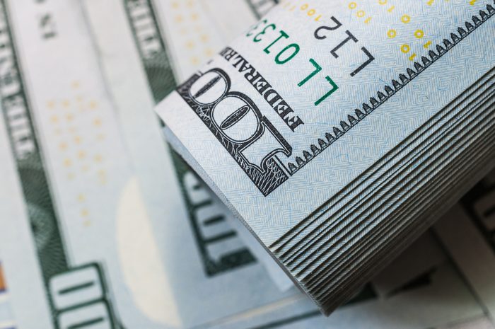 Roll of hundred dollar bill on dollar bills background.