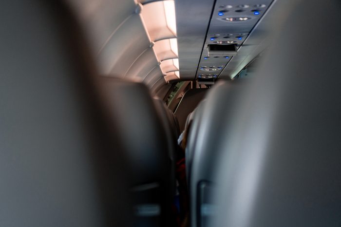 View of the roof and seats at an airplane with the lights on