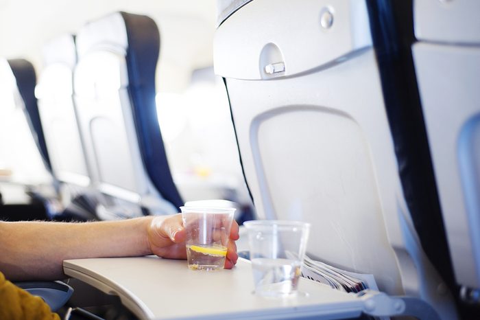 Happy man seating in the aircraft and drinking water before his trip abroad.