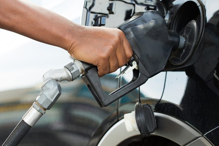 A man's hand filling up a car with gas or petrol at a gas station.