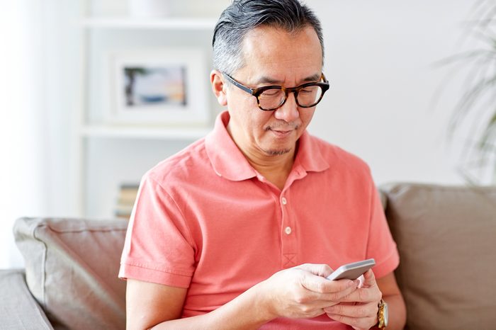 technology, people, lifestyle and communication concept - man with smartphone sitting on sofa at home