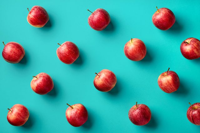 Colorful fruit pattern of fresh red apples on blue background. From top view