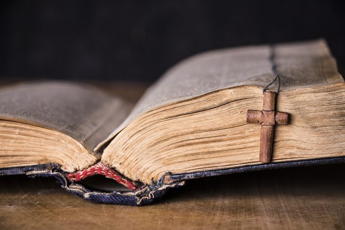 Brown cross on the Bible on a wooden background. Holy book.