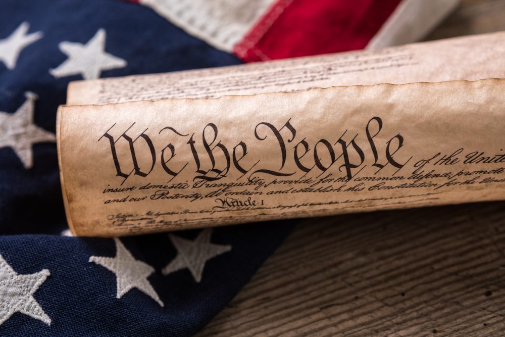 United States Constitution, rolled in a scroll on a vintage American flag and rustic wooden board