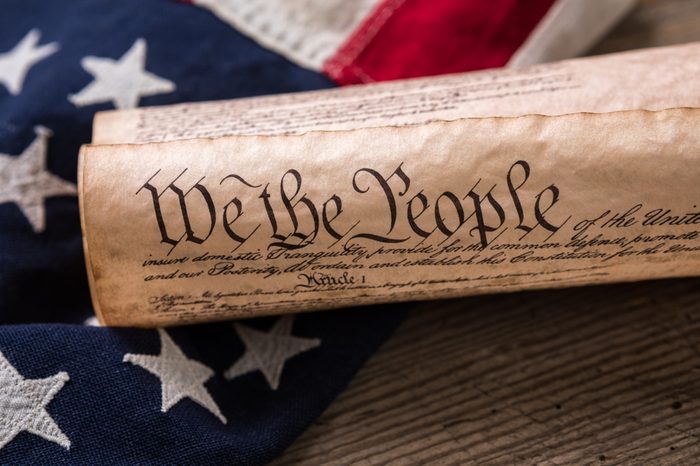 United States Constitution, rolled in a scroll on a vintage American flag and rustic wooden board