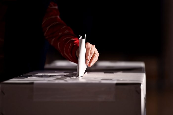 Hand of a person casting a vote into the ballot box during elections