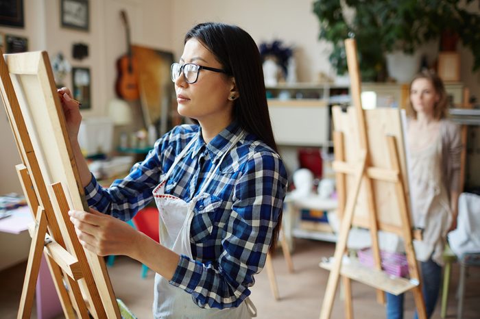 Serious young woman painting at art studio