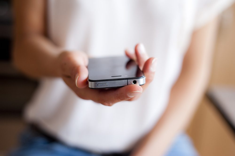 Close up of young woman handing smartphone. 