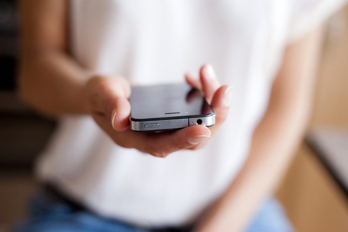 Close up of young woman handing smartphone.