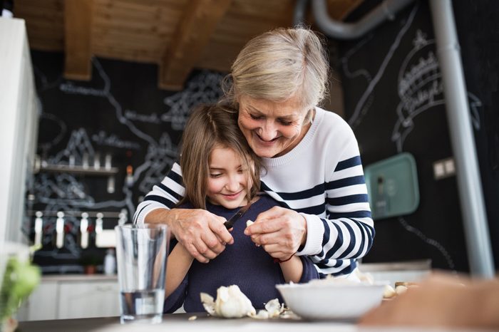 A small girl with grandmother cooking at home.