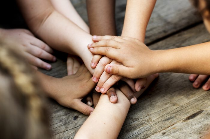 Diverse hands are join together on the wooden table