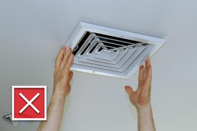 Close up man hand installing vent cover from ceiling Mounted Air Conditioner.