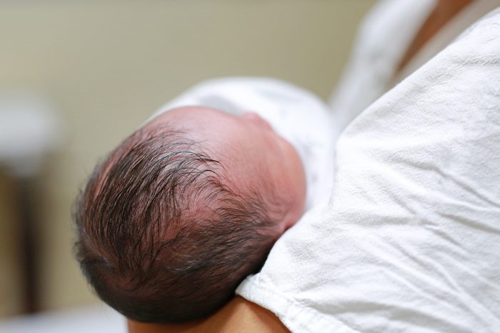 Asian mother carrying infant in hospital after delivery room.