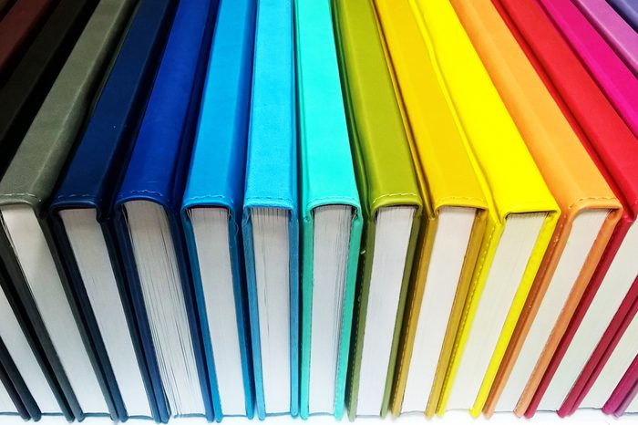 Books. A lot of books with bright covers in one pile isolated on white background. Design element, paper and leather texture. Colorful books on the shelf, close up