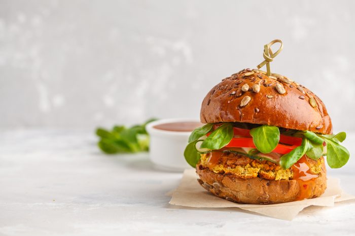 Vegan lentils burger with vegetables and curry sauce. Light background, copy space. Vegan food concept.