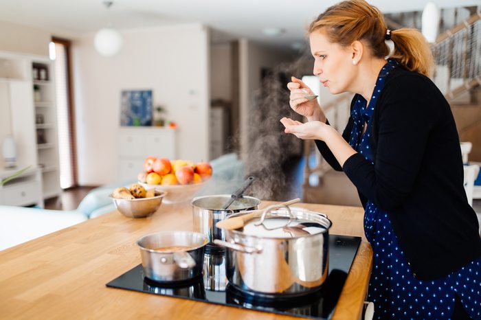 Housewife tasting food being made in modern kitchen