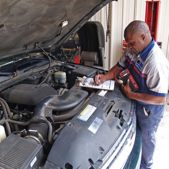 Auto mechanic performing a routine service inspection in a service garage.