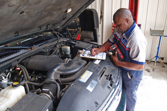 Auto mechanic performing a routine service inspection in a service garage.