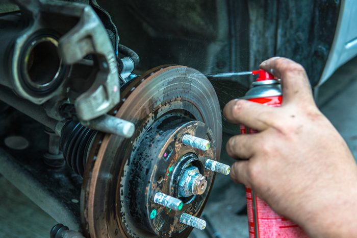 Close up mechanic repairing disk break with spraying oil