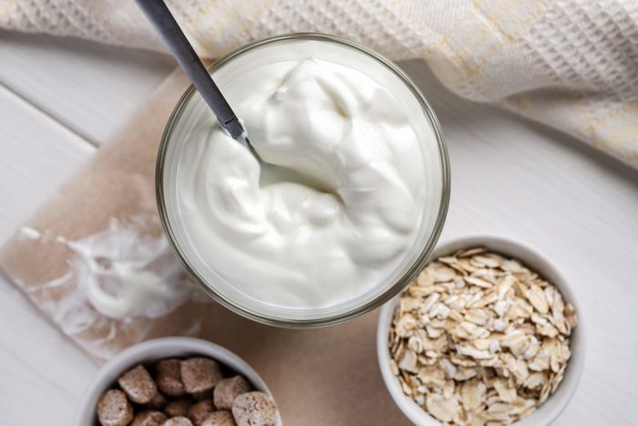 Yogurt with wheat bran and oat flakes on a wooden table, top view.