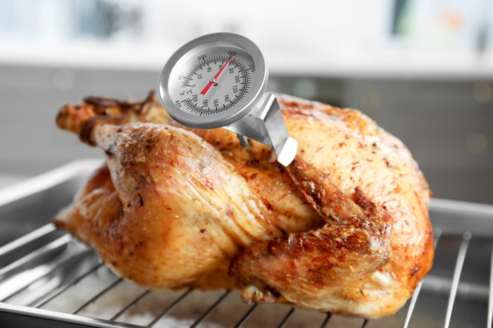 Golden roasted turkey on baking tray with a meat thermometer